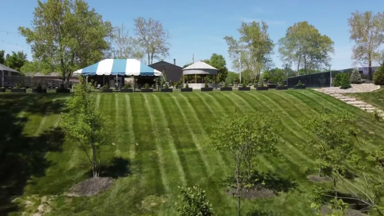 Manicured lawn with striped tent and ceremony area