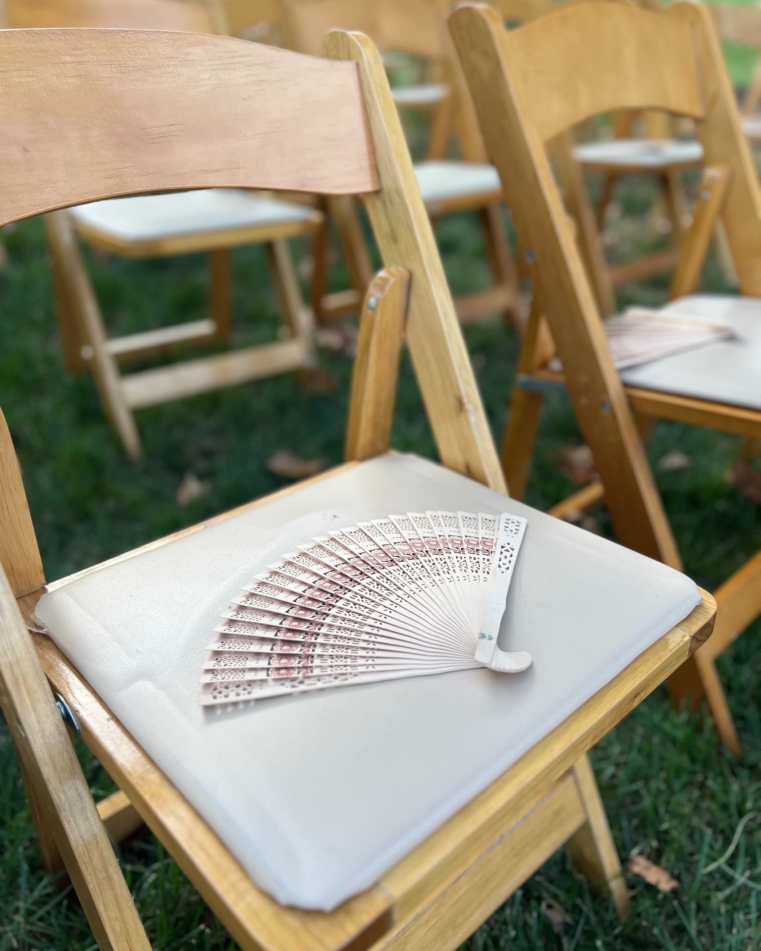 Ceremony chair detail with decorative fan program for summer wedding